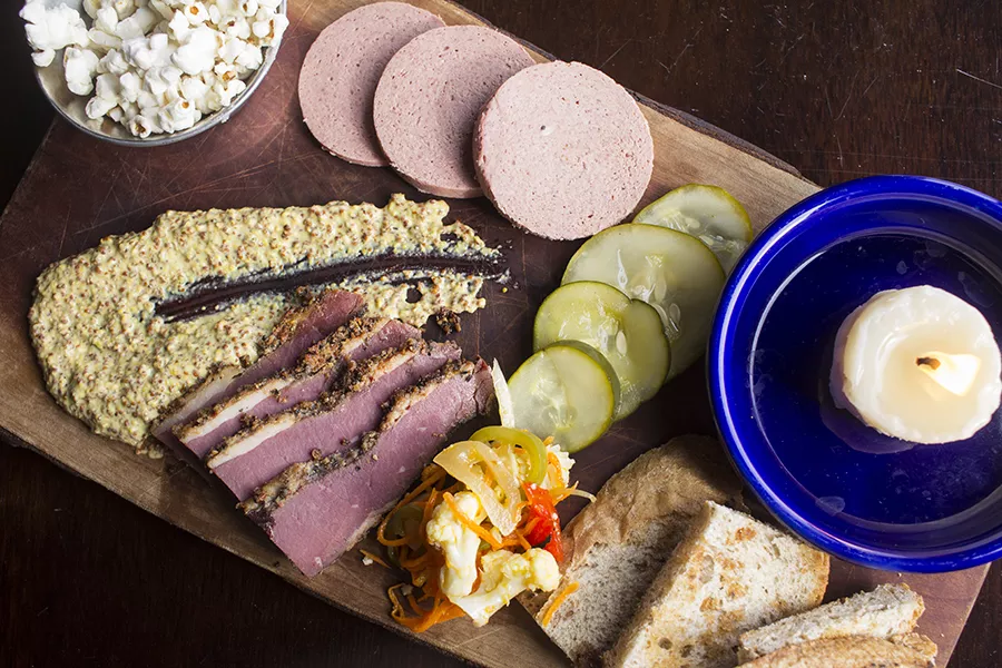 The house-cured meat platter features pastrami and braunschweiger, with pickles, giardiniera, and bacon-fat popcorn. - PHOTO BY MABEL SUEN