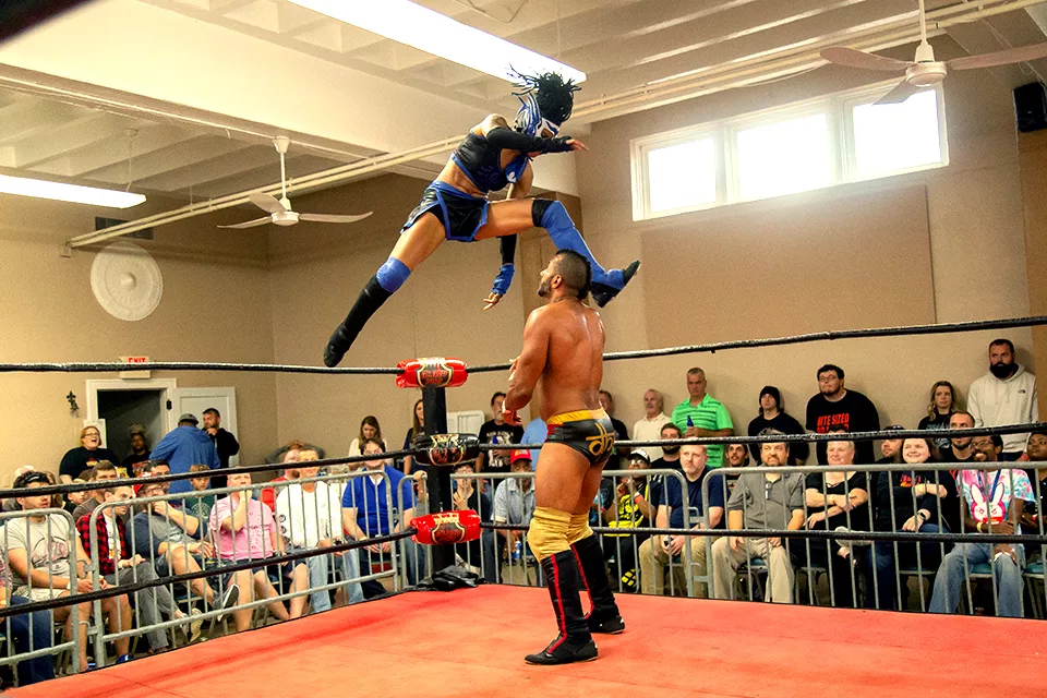 Clad in a white and blue lucha libre mask, Seishin delivers a flying kick to Hakim Zane. - MONICA MILEUR