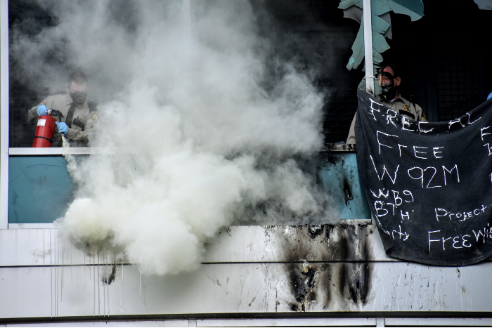 A St. Louis sheriff's deputy uses a fire extinguisher on burning debris. - DOYLE MURPHY