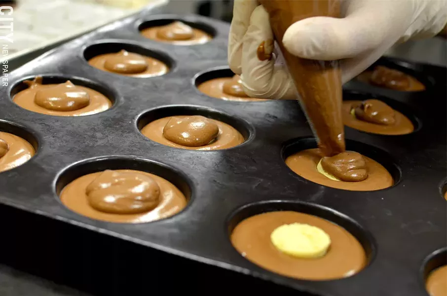 Baran fills molds with chocolate. - PHOTO BY MATT DETURCK
