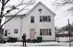 Mike Furlano, an attorney with the Legal Aid Society of Rochester, photographs the damaged exterior of 445 Sherman Street. - PHOTO BY MAX SCHULTE