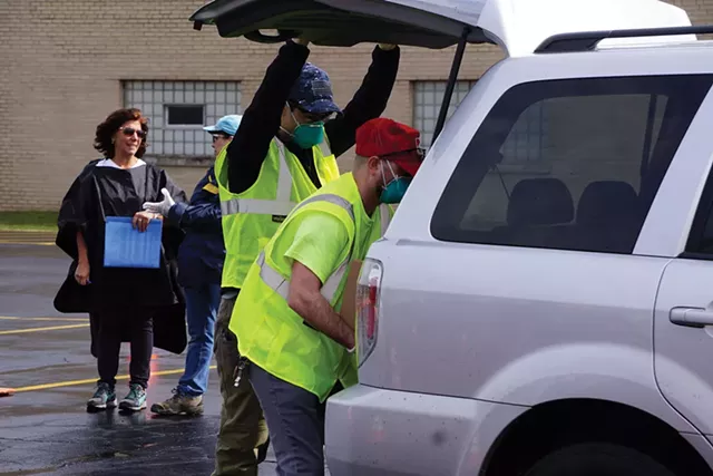 Foodlink volunteers load a 50-pound box of food into a vehicle during an emergency food distribution at Irondequoit Town Hall last week. - PHOTO BY GINO FANELLI