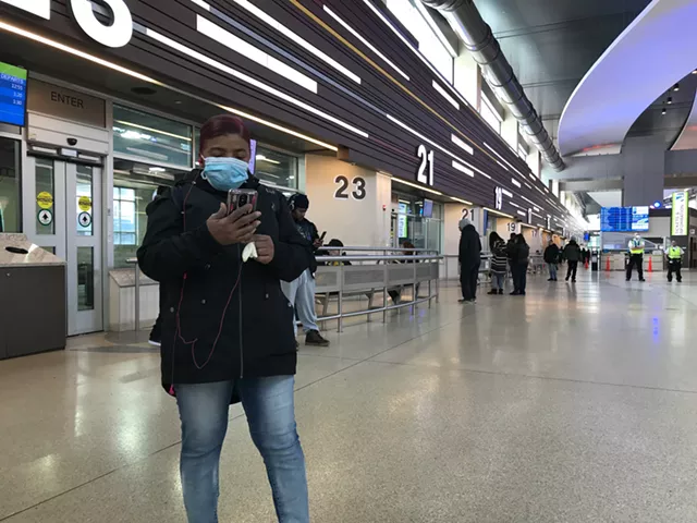 An RTS rider wearing a face mask peruses her phone while waiting for a bus at the downtown Transit Center. - PHOTO BY DAVID ANDREATTA