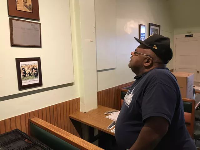 James Brown gazes at a silver-plated replica of a 1998 CITY Newspaper article that hung on the wall of his James Brown's Place diner and he credits with changing his life. - PHOTO BY DAVID ANDREATTA