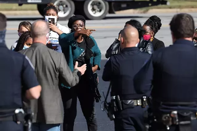 Free the People Roc organizer Stanley Martin confronts officers in the Rochester Police Locust Club parking lot. - PHOTO BY MAX SCHULTE