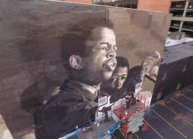 Painters depict a young John Lewis in the mural "I Am Speaking," at 49 State St. in downtown Rochester. - PHOTO BY MAX SCHULTE / WXXI NEWS