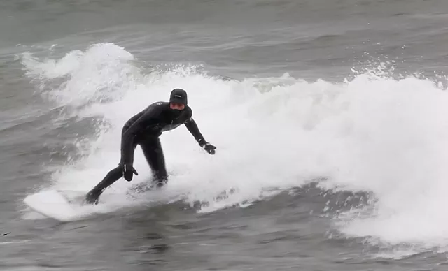 Aurelien Bouche Pillon surfs Lake Ontario in the dead of winter. - PHOTO BY MAX SCHULTE / WXXI NEWS