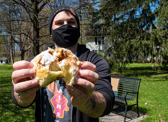 Jon Olek of Black Cat Baking Co., seen here with a cinnamon roll, works from his basement commercial-grade kitchen to supply several area cafes and shops with home-made pastries. - PHOTO BY JACOB WALSH