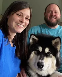 Sara and Brian Trost of Greece with their dog, Gus. The 1-year-old Alaskan Malamute became stressed whenever he was separated from the Trosts. - PHOTO PROVIDED