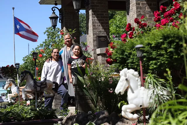 Carmen Rodriguez and Zenobio Rodriguez Jr. with their granddaughter, Milani, at their home at the corner of North and St. Jacob streets, where they have decorated their yard with more than 120 toy horses. - PHOTO BY MAX SCHULTE