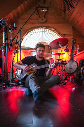 Lipp plays his resonator guitar at home in Temple Cabin Studios, where he records and produces music for himself and his friends. - PHOTO BY RYAN WILLIAMSON