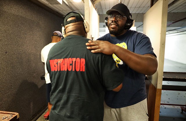 Ronnie Crawford gives a goodbye hug to Rochester African American Firearms Association Chief Instructor Mark Cochran. Crawford is an original member of RAAFA and owns a private security company. - PHOTO BY MAX SCHULTE