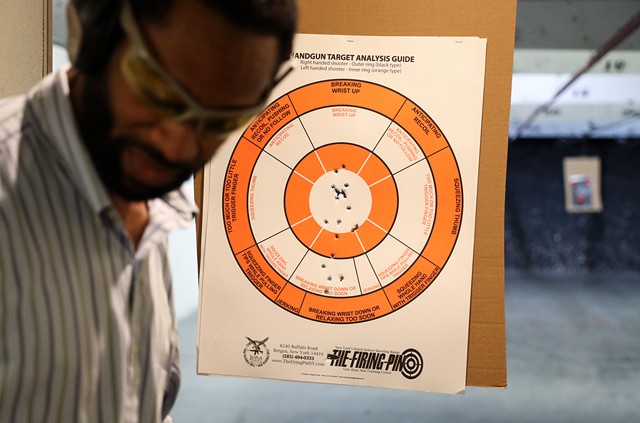 Quinn Lawrence, one of the self defense instructors with the Rochester African American Firearms Association, checks his target after shooting a pistol during practice at The Firing Pin. - PHOTO BY MAX SCHULTE