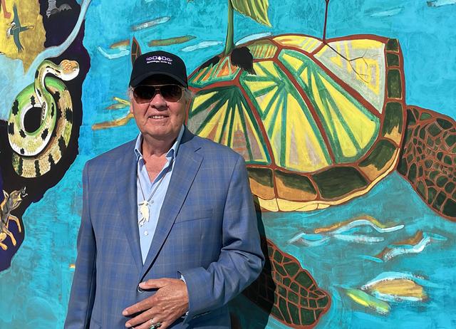 Artist Peter Jemison stands in front of his "Water is Life" mural, which was installed on the Floreano Convention Center facing the Genesee River. - PHOTO BY REBECCA RAFFERTY