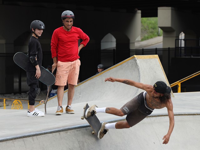 Skateistan instructor Farzad Sharafi stands with Rochester International Academy student Mohammad watching some of the local skaters shred the bowl at the ROC City Skatepark. - PHOTO BY MAX SCHULTE