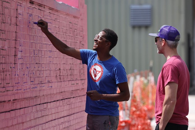 Shawn Dunwoody works on a mural on Scio Street while chatting with Blue Cease, executive director of the Rochester Contemporary Art Center. Dunwoody is the lone artist advising the effort to create a downtown BID. Case is a leading critic of the plan. - PHOTO BY MAX SCHULTE