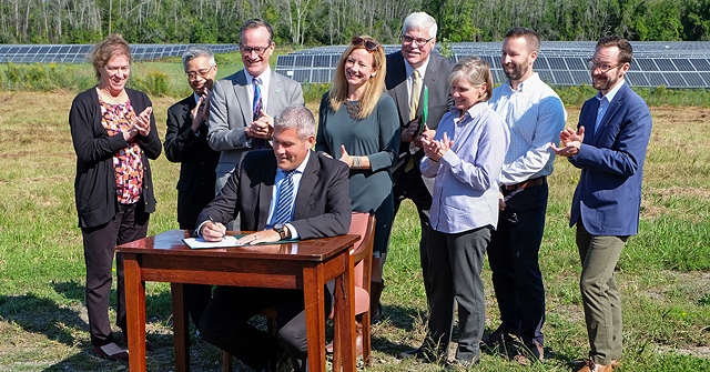 County Executive Adam Bello signs Monroe County's first climate action plan during a news conference. The event took place at a county-owned solar farm. - PHOTO BY JEREMY MOULE