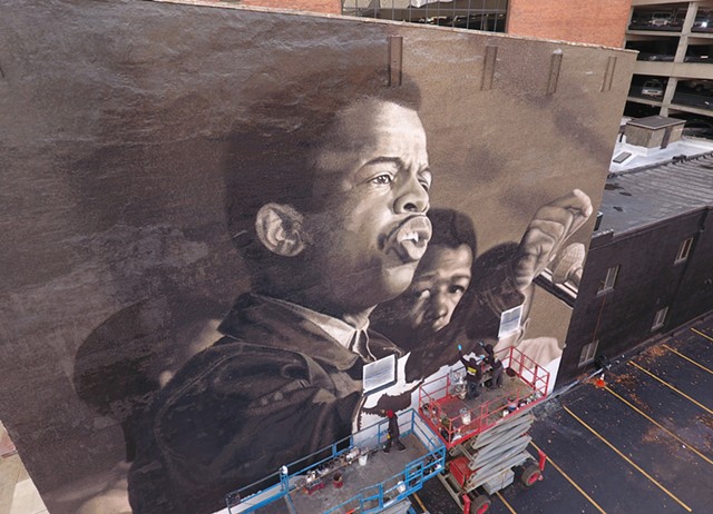 Rochester native Ephraim Gebre, along with fellow artists Darius Dennis, Dan Harrington, and Jared Diaz, bring John Lewis to life in a mural inspired by an image taken by Civil Rights-era photographer Danny Lyon. The mural, titled "I am Speaking," went up on State Street in downtown Rochester in 2020. It was not funded by the city's "percent-for-art" fund.