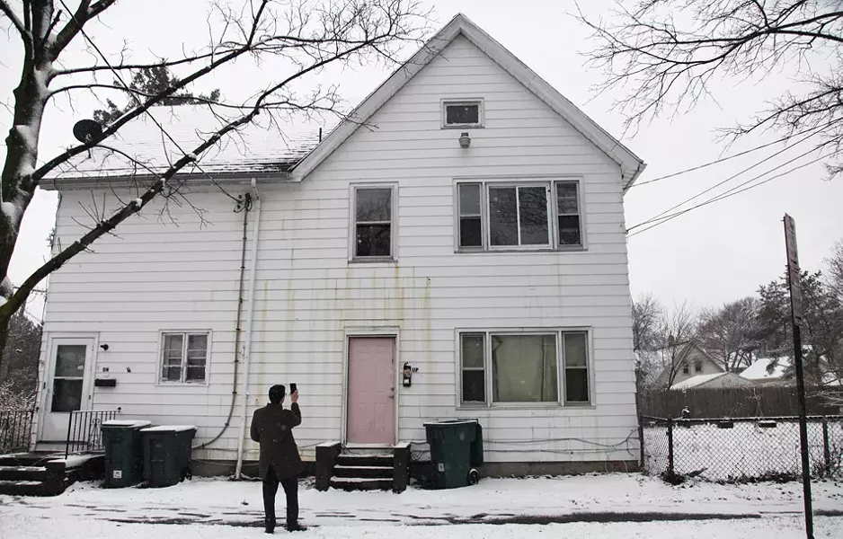 Mike Furlano, an attorney with the Legal Aid Society of Rochester, photographs the damaged exterior of 445 Sherman Street. - PHOTO BY MAX SCHULTE