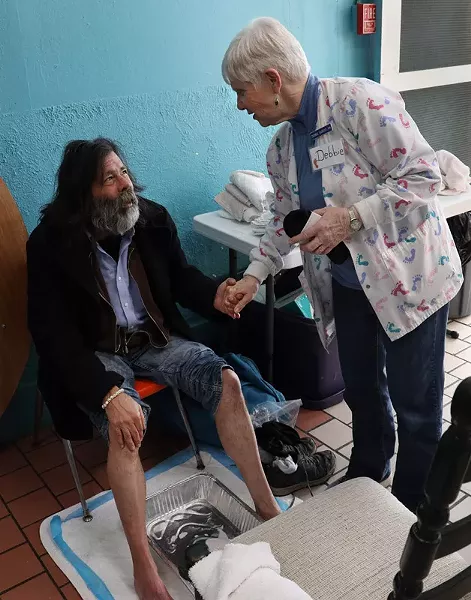 Debbie Sigrist, founder of the St. Joseph's House of Hospitality foot clinic, greets a guest. - PHOTO BY MAX SCHULTE