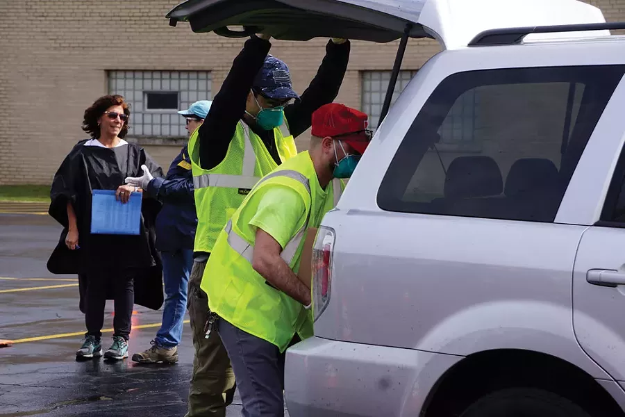 Foodlink volunteers load a 50-pound box of food into a vehicle during an emergency food distribution at Irondequoit Town Hall last week. - PHOTO BY GINO FANELLI