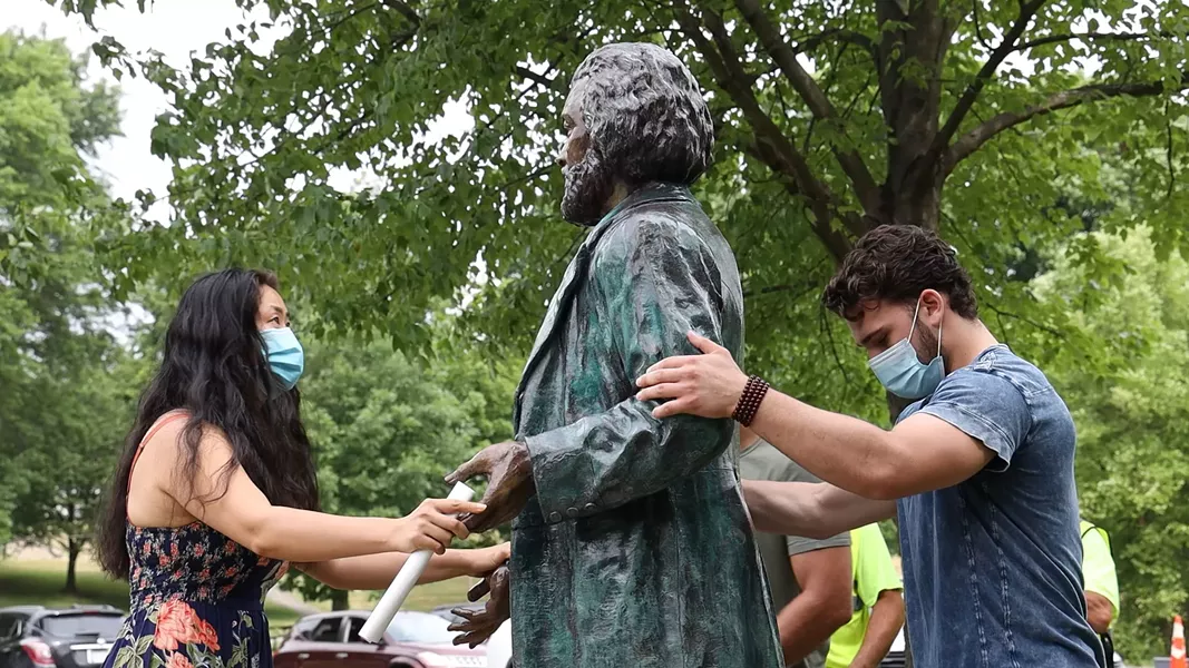 Sculptor Olivia Kim moves her statue of Frederick Douglass into position with help from John Boedicker. - PHOTO BY MAX SCHULTE