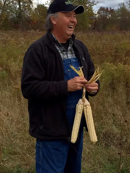 G. Peter Jemison, site manager at Ganondagan, braids together three ears of husked Iroquois White Corn. - PHOTO PROVIDED