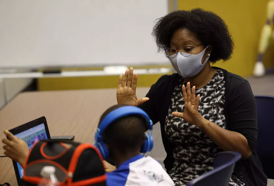 Brittany Rumph gives first-grader T'Aires Cheek a visual reminder that his next virtual class begins in 10 minutes. - PHOTO BY MAX SCHULTE / WXXI NEWS