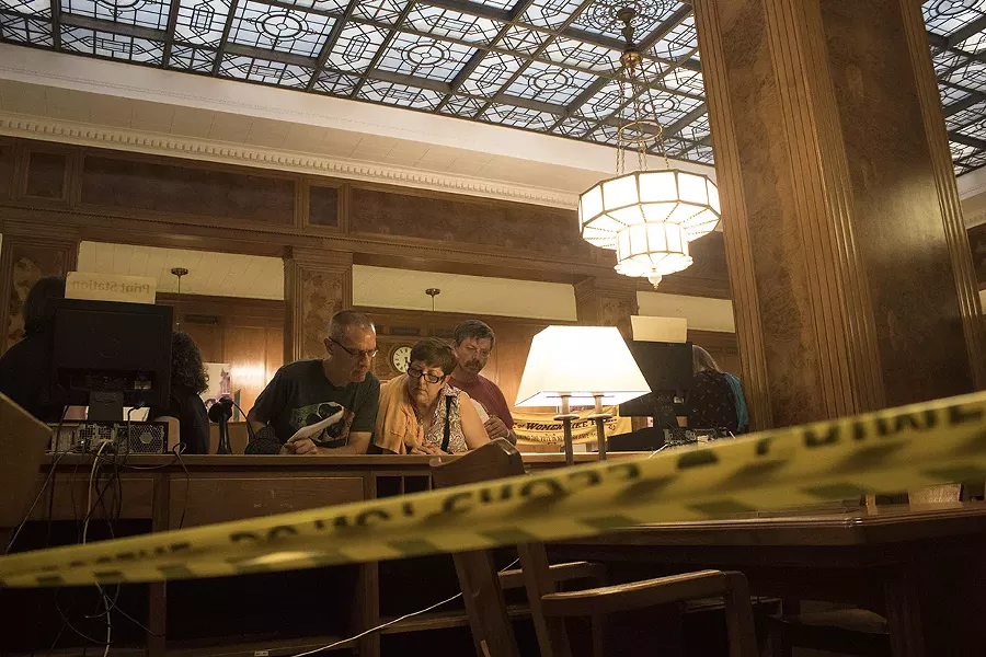 People examine clues during the Murder Mystery at the Central Library. - PHOTO BY ASHLEIGH DESKINS