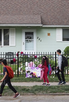 A group of children walk past a house on 221 Emerson St. where 16-year-old Zahira Smith was shot while attending a birthday party.