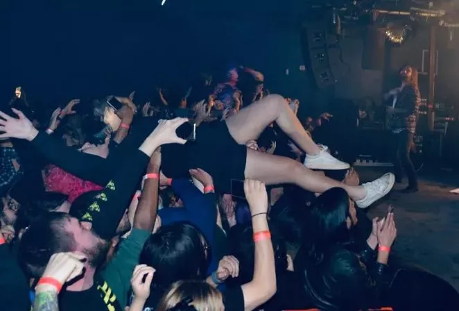 A girl lands in the crowd after stage diving as the lead singer from Every Time I Die rocks out. - CHRIS CONDE