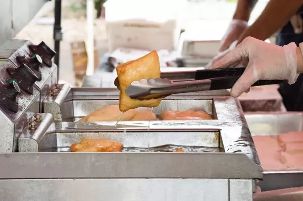 Ortega removes the beignets from the fryer while the pastry finishes cooking. - LEA THOMPSON