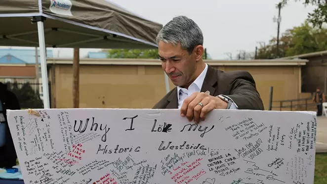 Mayor Ron Nirenberg reads a poster board at an Alazan Courts festival March 2. - BEN OLIVO / HERON