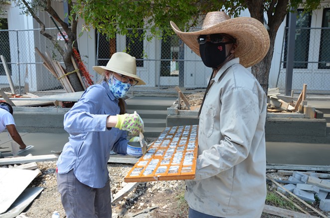 Artist Anne Wallace brushes mineral oil on a concrete stamp held by her helpful friend Antwan Nicholson. - BRYAN RINDFUSS