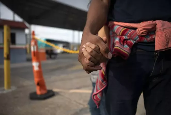 A Honduran asylum seeker holds his daughters’ hand at an immigration checkpoint in Nuevo Laredo. The pair were promptly returned to Mexico to await a court hearing under the Migrant Protection Protocols. - MIGUEL GUTIERREZ JR./THE TEXAS TRIBUNE