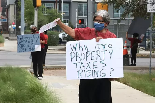 Rebecca Flores protests public facility corporations outside the H-E-B SoFlo Market on Saturday.