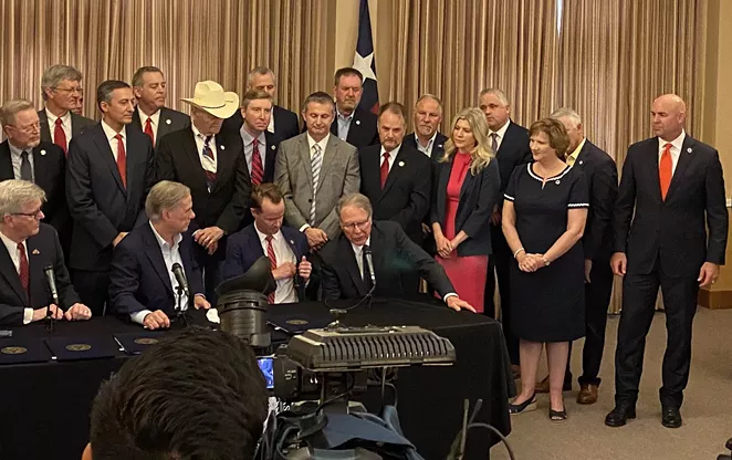 Their master's voice: Lt. Gov. Dan Patrick and Gov. Greg Abbott listen intently as NRA chief Wayne LaPierre praises their work. - SANFORD NOWLIN