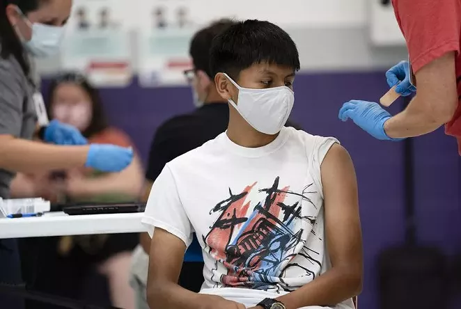 Anthony Peña, 15, sits after receiving a dose of the Pfizer vaccine at a clinic organized by the Travis County Mobile Vaccine Collaborative at Rodriguez Elementary School on July 28. - TEXAS TRIBUNE / SOPHIE PARK