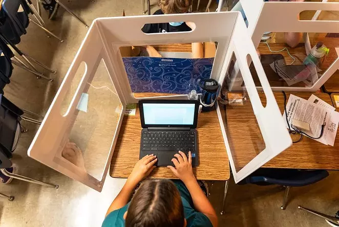 A fifth grader at Jacob’s Well Elementary School in Wimberley works on their laptop behind a clear barrier meant to stop the spread of COVID-19 on September 4, 2020. - TEXAS TRIBUNE / JORDAN VONDERHAAR