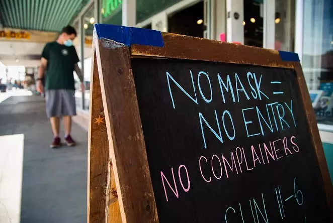 A sign outside of a South Austin store asked customers to follow COVID-19 precautions on March 3, 2021. - TEXAS TRIBUNE / EVAN L'ROY