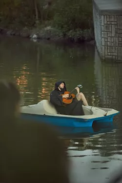 Ethan Smith plays the guitar while floating down the river. - SA HERON / TYLER SMITH