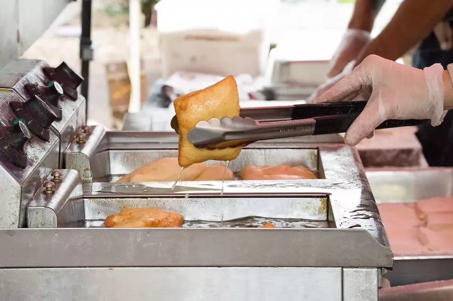 Ortega removes the beignets from the fryer while the pastry finishes cooking. - LEA THOMPSON