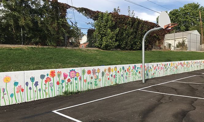 A row of hand-painted flowers brighten a playground - retaining wall at Dilworth Elementary. - BRYANT HEATH
