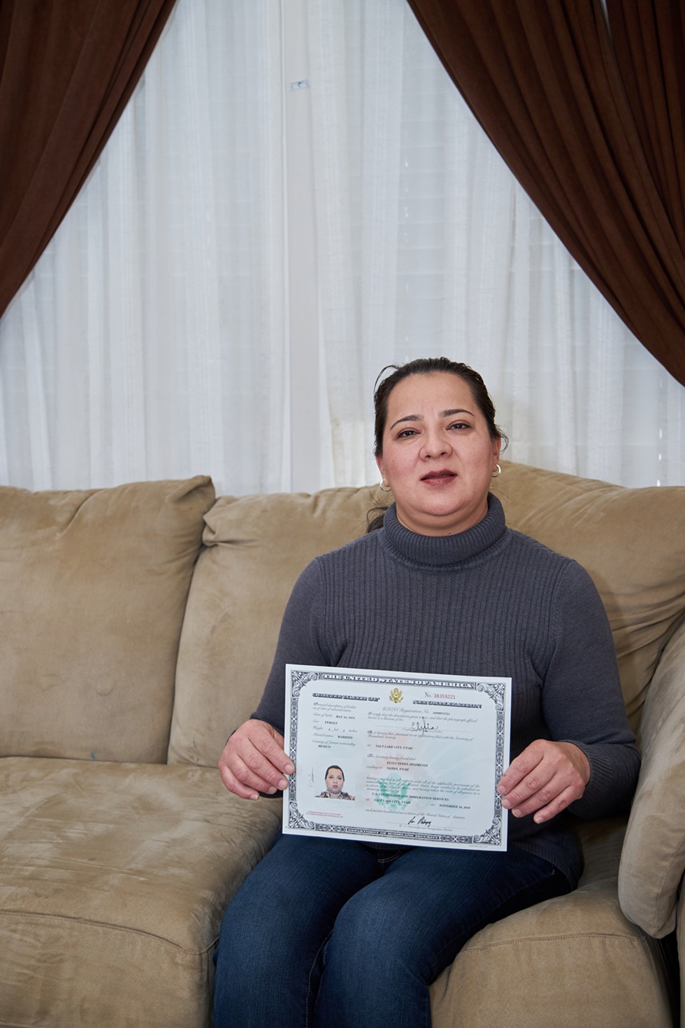 Elvia Perez Arizmendi holds up her Certificate of Citizenship inside her Sandy Home. - SARAH ARNOFF