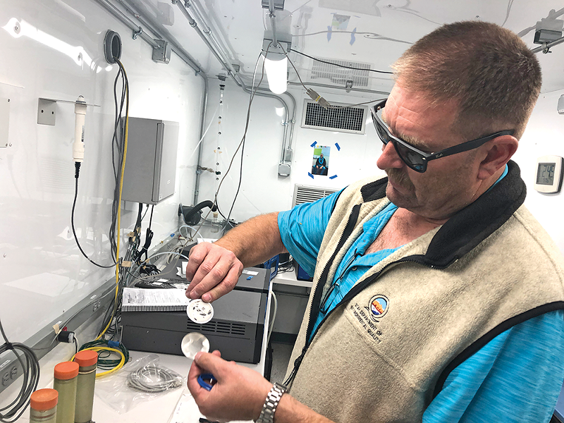 Bo Call shows off a filter from one of the state’s machines. He says his monitoring devices are more precise, but, “We don’t have one on every street corner. PurpleAir, you can have all over the place.” - KELAN LYONS