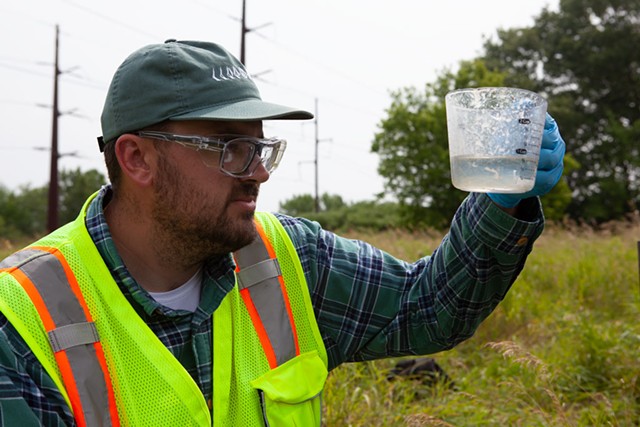Aaron Sutton tests a well outside the Air National Guard base in Burlington last week. Sutton works for Parsons Corp., the environmental firm performing a range of tests to see if contamination on the base has migrated toward the Winooski River. - KEVIN MCCALLUM