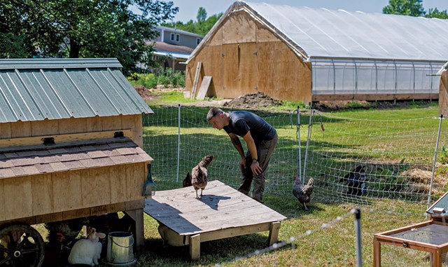 Kyle Bowley looking at chickens in a coop - GLENN RUSSELL