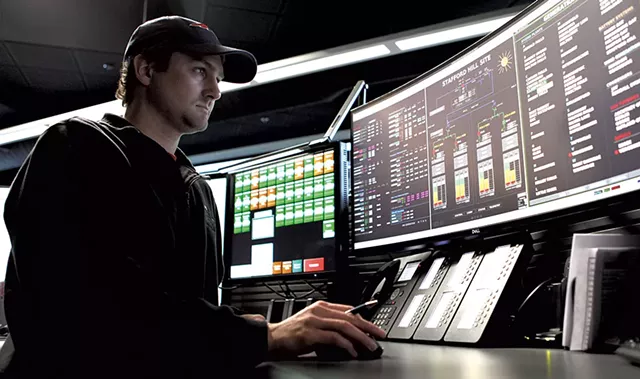 Nick Stanhope checking the status of one of Green Mountain Power's grid-level batteries - KEVIN MCCALLUM