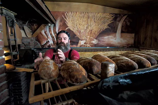 Trent Cooper placing a freshly baked sourdough bâtard on a cooling rack in Westford - GLENN RUSSELL