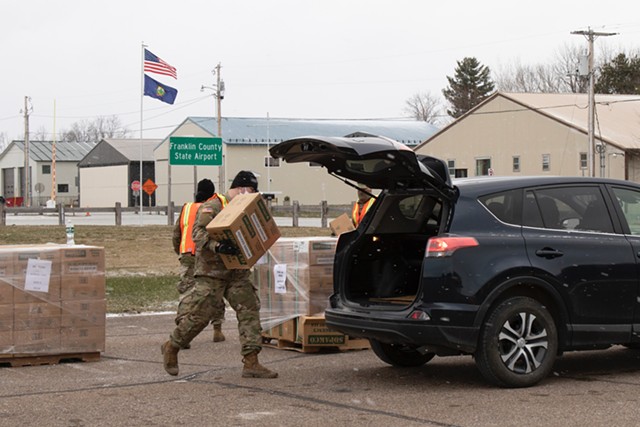 A member of the Vermont National Guard loading a case of MREs into a car in Swanton on April 22 - COURTESY OF VERMONT NATIONAL GUARD